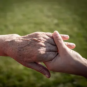 young holding a hand of senior